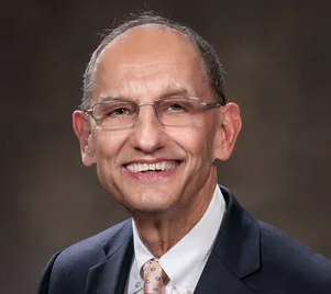 A man in suit and tie smiling for the camera.