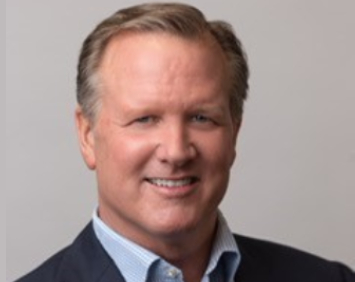 A man in a suit and tie smiling for the camera.