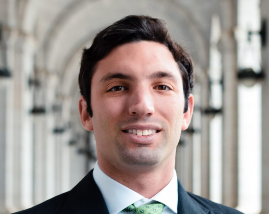 A man in suit and tie standing under an archway.