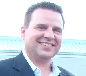 A man in a suit and tie smiling for the camera.